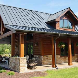 Front view of a typical mid-class home with an outdoor porch area and a light blue-ish, gray metal roof by McElroy
