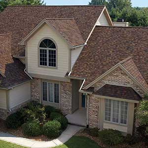 Front view of a typical mid-class home with red-ish, brown Owens Corning shingles on its roof